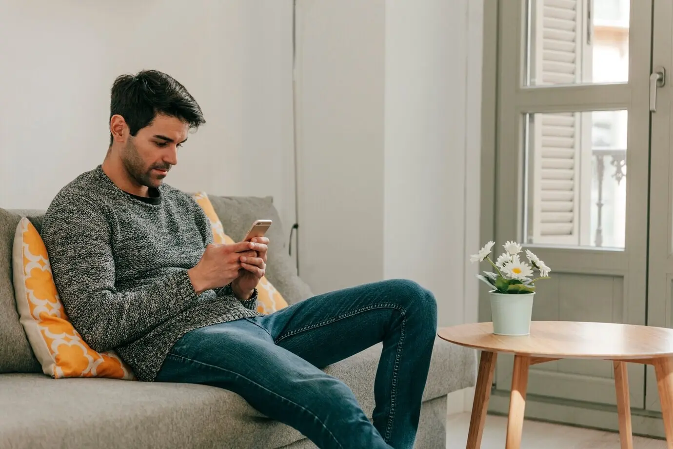 Mann mit Smartphone, auf einem Sofa ruhend