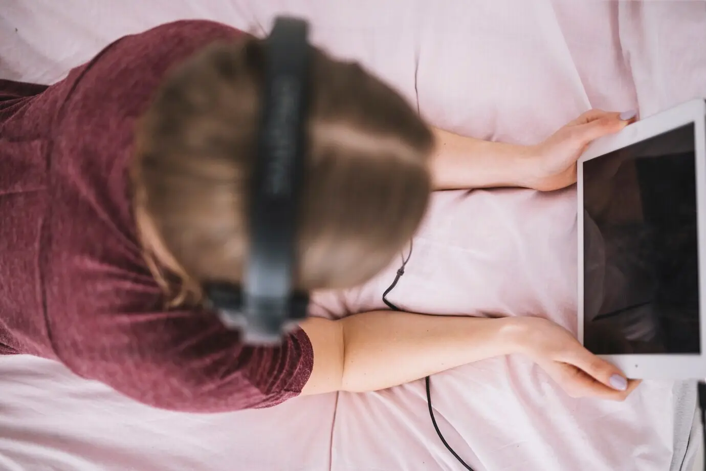 Nicht erkennbare Frau, die auf dem Bett ein Tablet benutzt.